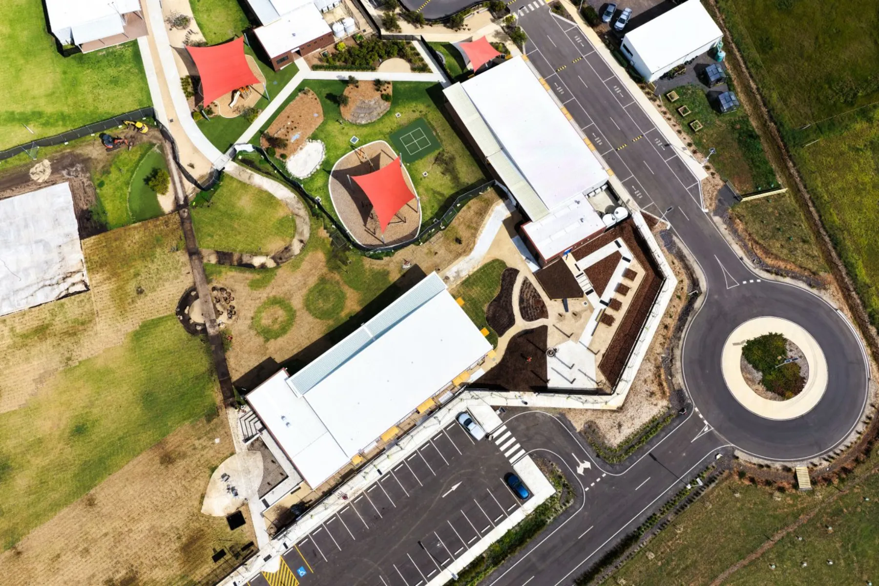 Top-down aerial of the campus showing the playground shade sails, the new landscaped grounds and the existing roundabout and car park