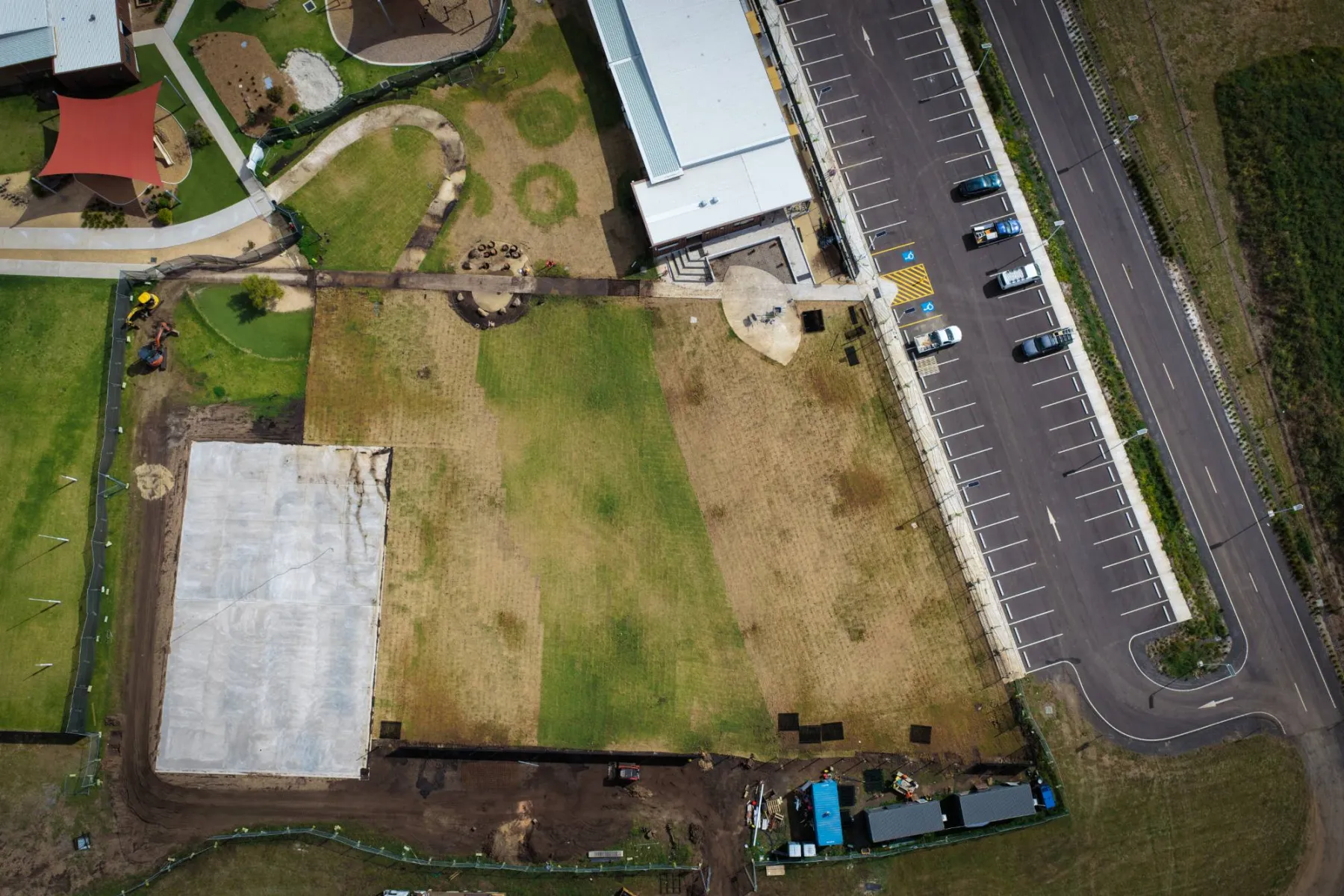 Top-down view of the turfed areas, the sports court slab, the existing car park and the perimeter earthworks